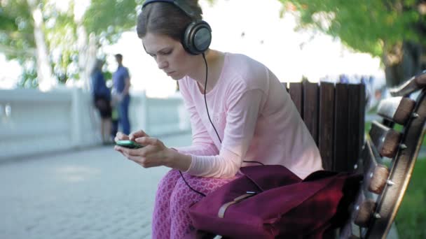 Junge, stylische, schöne Frau, die auf den Straßen der Stadt Musik mit Kopfhörern am großen Monitor hört. — Stockvideo