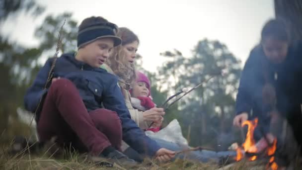 Szczęśliwa rodzina turystów na podróż. Mama i dzieci smażyć porcję na ogień w pobliżu namiotu — Wideo stockowe