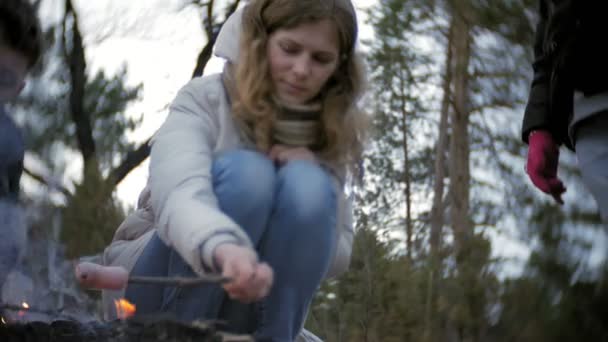 Šťastná rodina turistů na cestě. Máma a děti osmahneme klobásy do ohně u stanu — Stock video