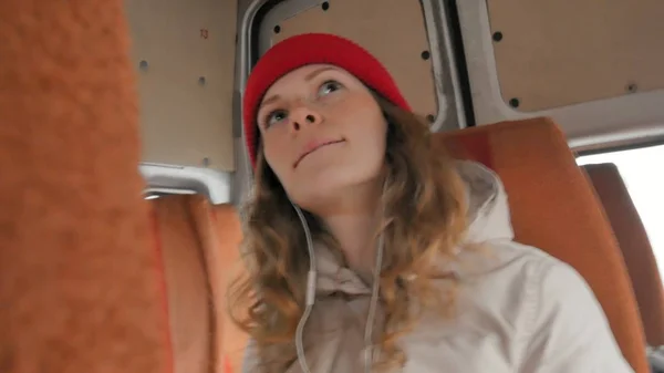 Νεαρή γυναίκα χαρούμενη Ταξιδεύοντας με το λεωφορείο σε μια θλιβερή ημέρα. Κοιτάζει έξω από το παράθυρο — Φωτογραφία Αρχείου
