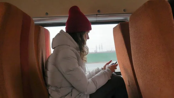 Jeune femme joyeuse avec un chapeau rouge, voyageant en bus un jour triste. Elle écoute de la musique — Photo