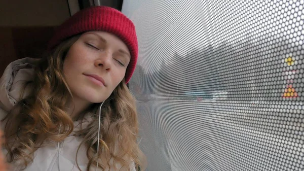 Νεαρή γυναίκα χαρούμενη Ταξιδεύοντας με το λεωφορείο σε μια θλιβερή ημέρα. Κοιτάζει έξω από το παράθυρο — Φωτογραφία Αρχείου