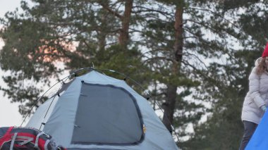 Çekici genç turist kadın kırmızı şapkalı bir turist çadır forest yakınındaki sahil üzerinde toplar.