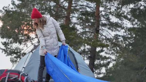 赤い帽子の魅力的な若い観光客女性が海岸の森の近くの観光テントを収集します。 — ストック写真