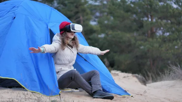 赤い帽子の魅力的な若い女性観光客観光テントで座っているし、仮想現実ヘルメットを楽しんでいます — ストック写真