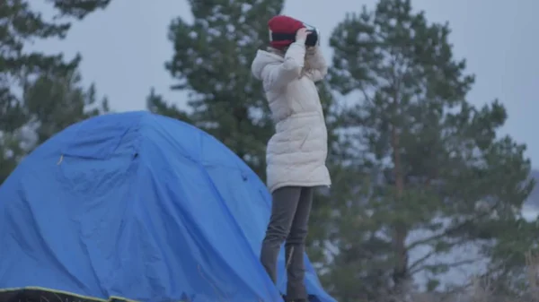 Atractiva joven turista con sombrero rojo se sienta en una carpa turística y disfruta de un casco de realidad virtual —  Fotos de Stock