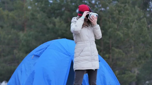 Kırmızı bir şapka çekici genç kadın turist turist çadırda oturur ve bir sanal gerçeklik kask sahiptir — Stok fotoğraf