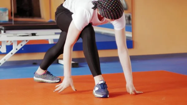 En attraktiv kvinna gör stretching på en simulator i sport gym — Stockfoto