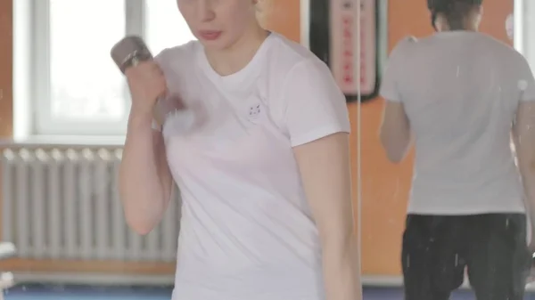 Naispotkunyrkkeilijä treenaa urheilustudiossa käsipainoilla. — kuvapankkivalokuva