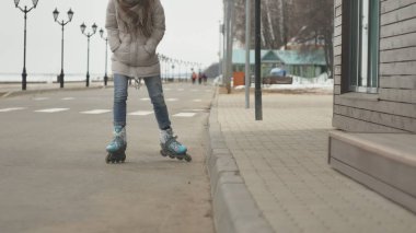 Sportif sıcak giysiler ve Silindirler, deniz kenarı yolda sürme giyen genç güzel kadın kırmızı şapkalı