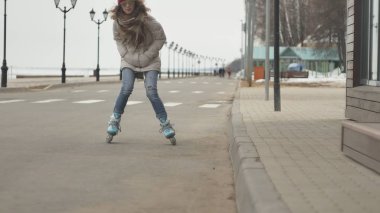 Sportif sıcak giysiler ve Silindirler, deniz kenarı yolda sürme giyen genç güzel kadın kırmızı şapkalı