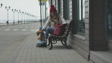 Sportif sıcak giysiler ve Silindirler, deniz kenarı yolda sürme giyen genç güzel kadın kırmızı şapkalı