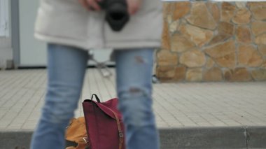 Kırmızı şapka giyen sportif sıcak giysiler ve silindirleri, asfalt yolda ve vintage fotoğraf makinelerinde fotoğraf çekimi oturan genç güzel kadın