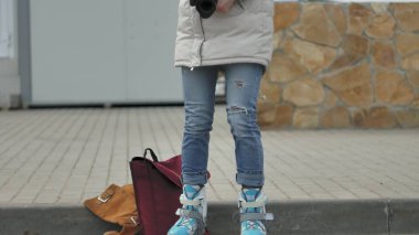 Kırmızı şapka giyen sportif sıcak giysiler ve silindirleri, asfalt yolda ve vintage fotoğraf makinelerinde fotoğraf çekimi oturan genç güzel kadın