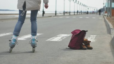 Sportif sıcak giysiler ve Silindirler, deniz kenarı yolda sürme giyen genç güzel kadın kırmızı şapkalı