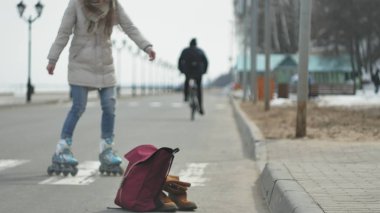 Sportif sıcak giysiler ve Silindirler, deniz kenarı yolda sürme giyen genç güzel kadın kırmızı şapkalı