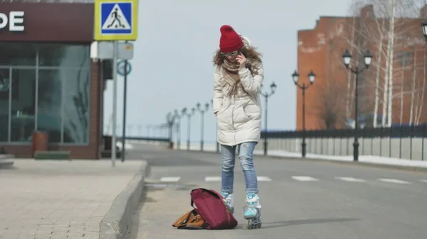 Giovane bella donna con un cappello rosso, indossa vestiti sportivi caldi e rulli, cavalcando sulla strada sulla costa — Foto Stock