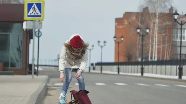 Joven hermosa mujer en un sombrero rojo, con ropa de abrigo deportivo y rodillos, a caballo en la carretera en la costa — Foto de Stock