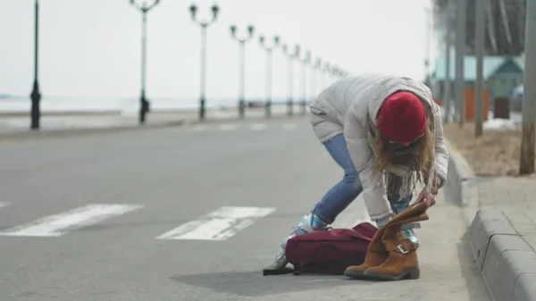 Giovane bella donna con un cappello rosso, indossa vestiti sportivi caldi e rulli, cavalcando sulla strada sulla costa — Foto Stock