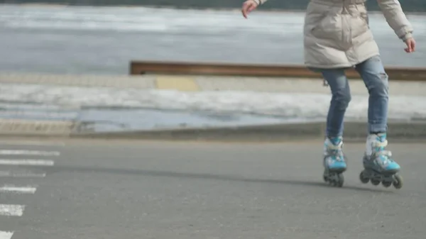 Mooie jongedame in een rode hoed, het dragen van sportieve warme kleren en rollen, rijden op de weg aan de kust — Stockfoto