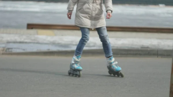 Junge schöne Frau mit rotem Hut, in sportlich warmer Kleidung und Rollschuhen, unterwegs an der Küste — Stockfoto