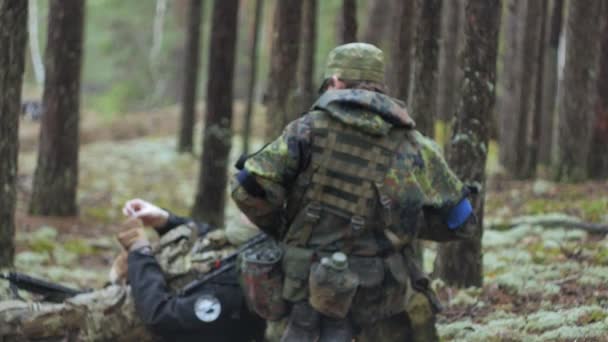 Soldados em camuflagem com armas de combate estão sendo disparados no abrigo da floresta, o conceito militar — Vídeo de Stock