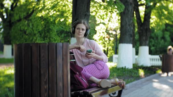 Young stylish beautiful woman, on city streets listening to music in large monitor headphones. — Stock Video