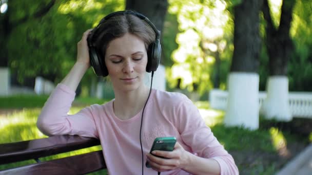 Jeune belle femme élégante, dans les rues de la ville à l'écoute de la musique dans les écouteurs grand moniteur . — Video