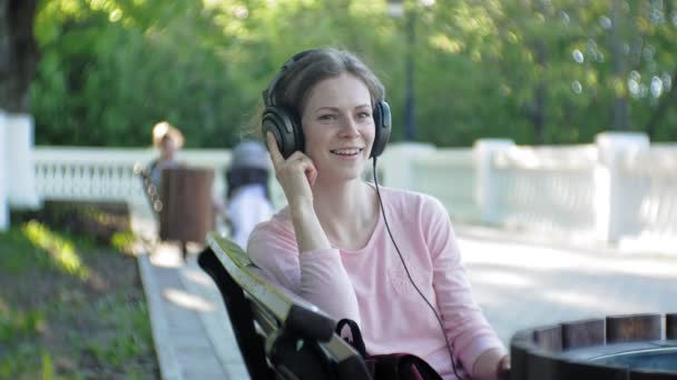 Jeune belle femme élégante, dans les rues de la ville à l'écoute de la musique dans les écouteurs grand moniteur . — Video