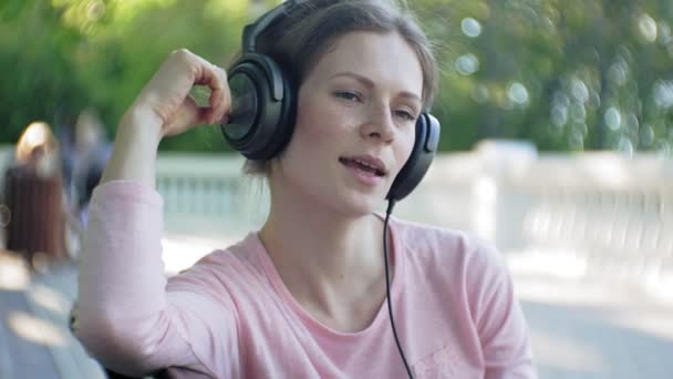 Κομψό όμορφη γυναίκα, στους δρόμους της πόλης να ακούτε μουσική στα ακουστικά μεγάλη οθόνη. — Αρχείο Βίντεο