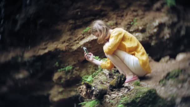 Mujer aventura de viaje tomando fotos de un teléfono inteligente en una cascada de montaña, disfrutando del hermoso paisaje de la naturaleza — Vídeos de Stock