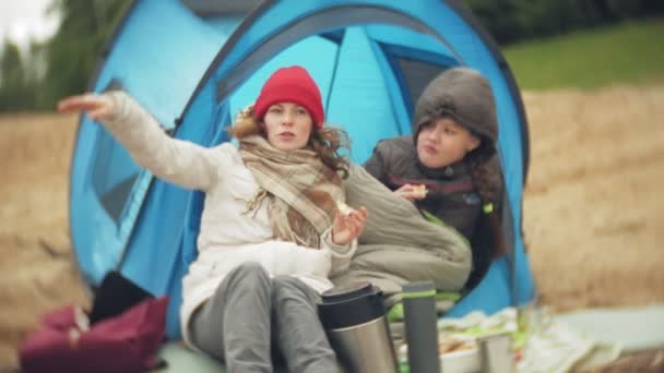 Nehir kıyısında turist çadır. yeme ve içme nehre bakar çadır yakınındaki iki kız oturuyor. — Stok video