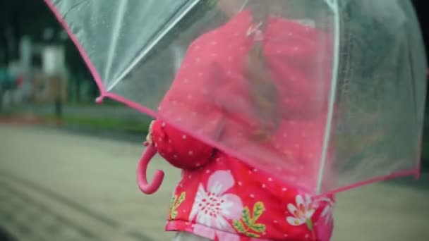 Όμορφο κοριτσάκι με ομπρέλα, παίζοντας στη βροχή, περπατώντας κατά μήκος της ακτής — Αρχείο Βίντεο
