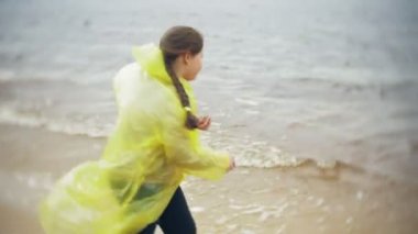 Mutlu kız sahil boyunca seyahat yaşam tarzı macera tatil açık havada yürüyüş. Bir moda sarı yağmurluk giymiş bir kız