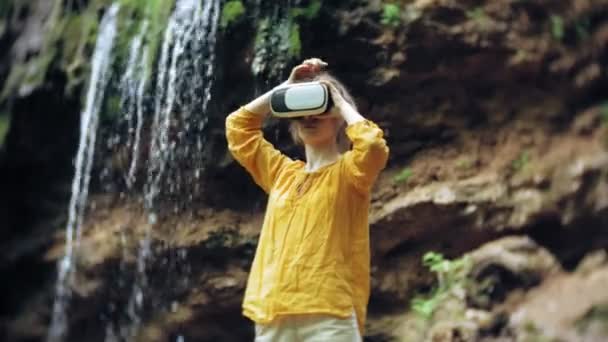 Girl virtual reality glasses VR sunny day wildlife woman raising hands peaks mountains, waterfall, forest electronic wearable technology using game simulator visual experience 3d cosmic innovation — Stock Video