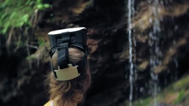 여자 가상 현실 안경 Vr 화창한 날 야생 여자 손 봉우리 산, 폭포, 숲 전자 착용 할 수 있는 기술 게임 시뮬레이터 시각적 경험 3d 우주 혁신을 사용 하 여 높이 — 비디오