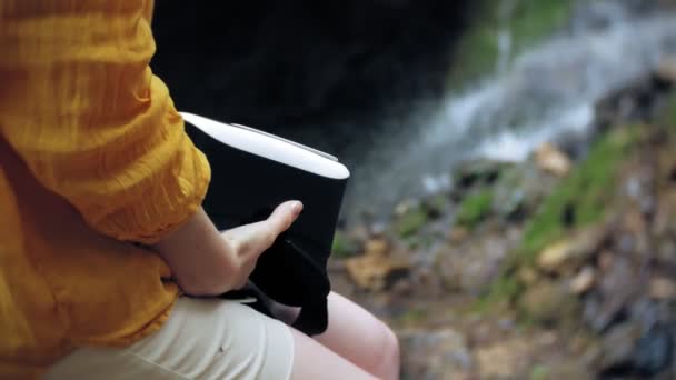 Fille réalité virtuelle lunettes VR ensoleillé jour faune femme levant les mains pics montagnes, cascade, forêt électronique portable technologie utilisant simulateur de jeu expérience visuelle 3d innovation cosmique — Video