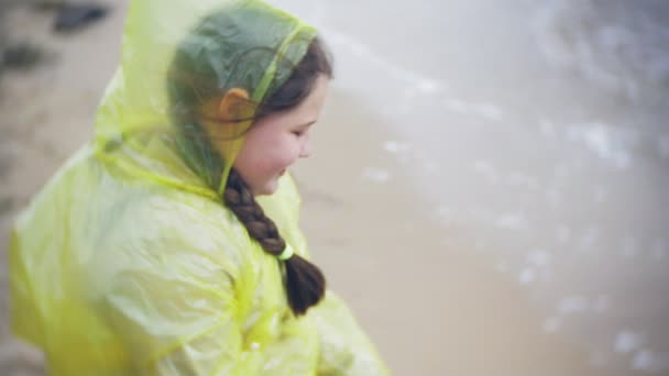 Chica feliz caminando a lo largo de la costa Viajar vacaciones aventura estilo de vida al aire libre. Una chica vestida con un impermeable amarillo de moda — Vídeos de Stock