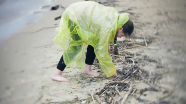 Gelukkig meisje wandelen langs de kust Lifestyle reizen avontuurlijke vakantie buitenshuis. Een meisje gekleed in een modieuze gele regenjas — Stockvideo