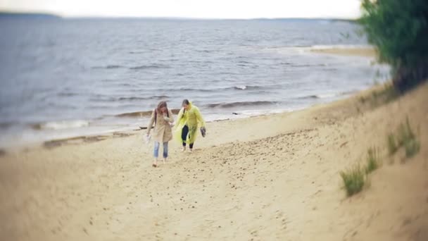 Glückliches Mädchen zu Fuß entlang der Küste unterwegs Lifestyle-Abenteuerurlaub im Freien. ein Mädchen in einem modischen gelben Regenmantel — Stockvideo