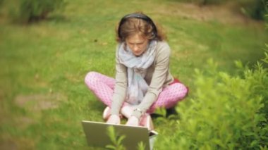 Kadın dizüstü bilgisayar ile çim çimen güzel yeşil park rahatlatır. Bir genç çok yıllık kadında bir dizüstü bilgisayar çalışan bir botanik bahçesi. Açık havada teknoloji