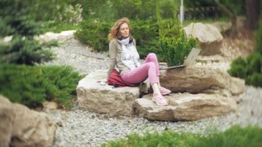 Bir kadın kulaklıklar müzik dinler, güzel bir yeşil park buzlu rahatlatır. Botanik Bahçesi genç bir çok yıllık kadın müzik dinliyor. Açık havada teknoloji