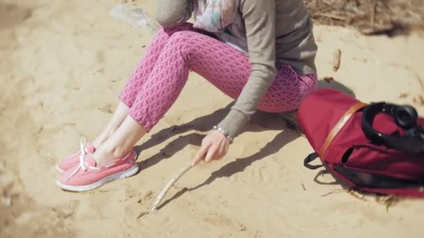 Una mujer escucha música en los auriculares, se relaja y baila en la orilla del río del mar del océano. Tecnología al aire libre — Vídeos de Stock