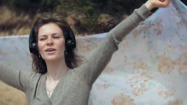 Une femme écoute de la musique sur des écouteurs, se détend et danse sur le rivage de la rivière de la mer de l'océan. La technologie en plein air — Video