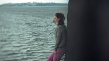 Bir kadın rahatlatır ve okyanus nehir kıyısında oturuyor. Açık havada teknoloji