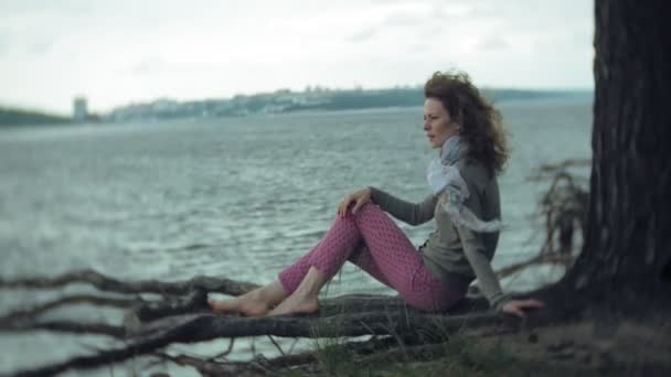 Женщина расслабляется и сидит на берегу океанской реки. Технологии на открытом воздухе — стоковое видео