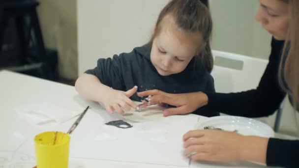 Dzieci dziewczyny razem usiąść przy stole w klasie i rysunek z ich palce i farby. Z nimi ich młoda i piękna Nauczycielka. — Wideo stockowe