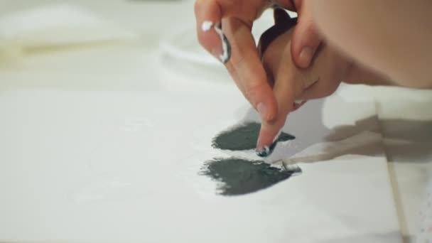 Kinderen-meisjes zitten samen aan tafel in de klas en de tekening met hun vingers en verf. Met hen hun jong en mooi leraar. — Stockvideo