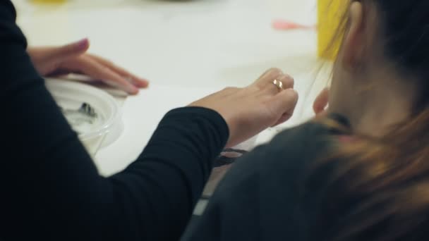 Kinderen-meisjes zitten samen aan tafel in de klas en de tekening met hun vingers en verf. Met hen hun jong en mooi leraar. — Stockvideo