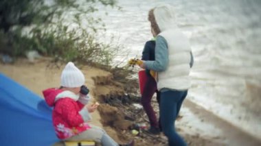 Nehir kıyısında bir turist çadır yakınındaki bir ukulele üzerinde güzel bir kızın ailesiyle birlikte çalış